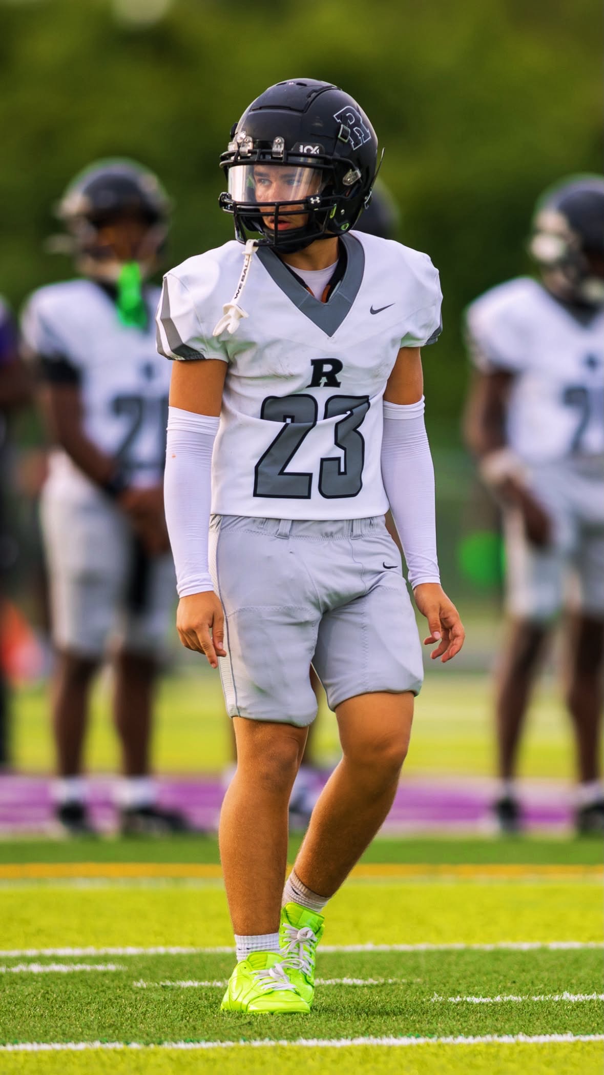Isaiah Alvelo standing on the football field in his white and gray uniform